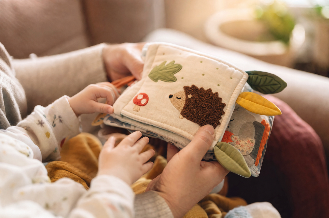 Parent and baby holding a soft fabric book with animal pictures